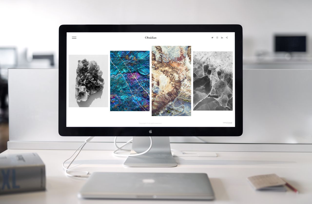 A contemporary office desk setup featuring a sleek computer monitor displaying abstract artwork.